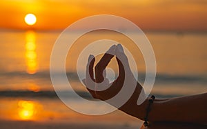 Adult woman do meditation the ocean beach at sunset Â close up